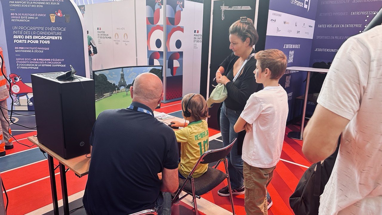 A child playing at the stand, watched by their family